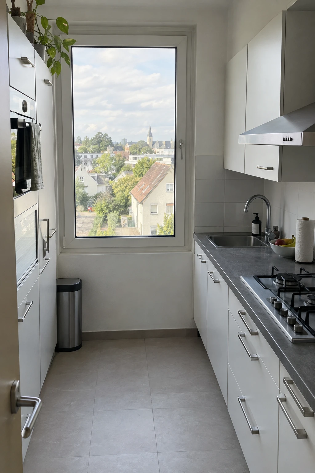 The original kitchen with white cabinets, gray countertops, and a tall window